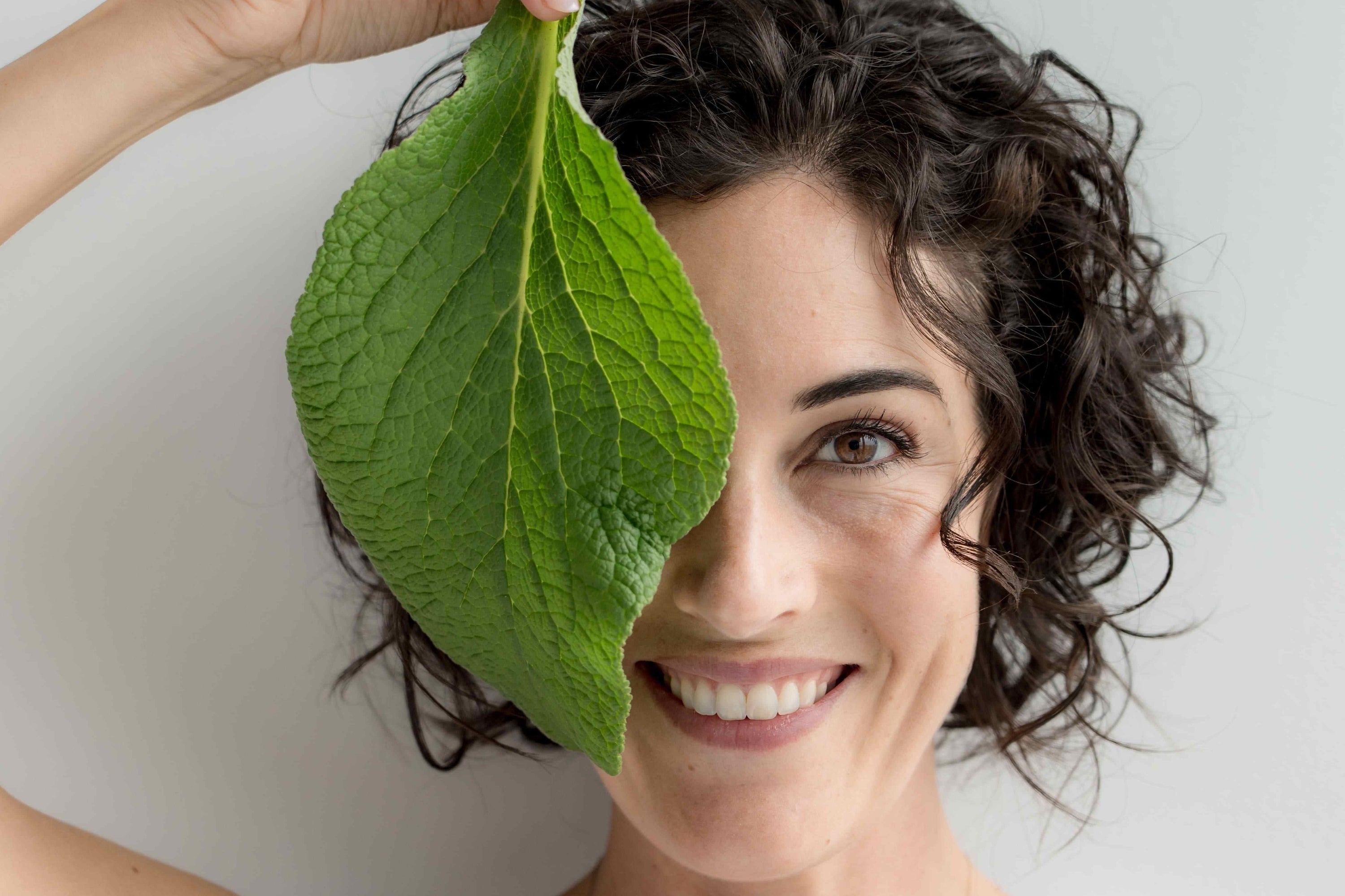 Femme qui tient une feuille devant son visage