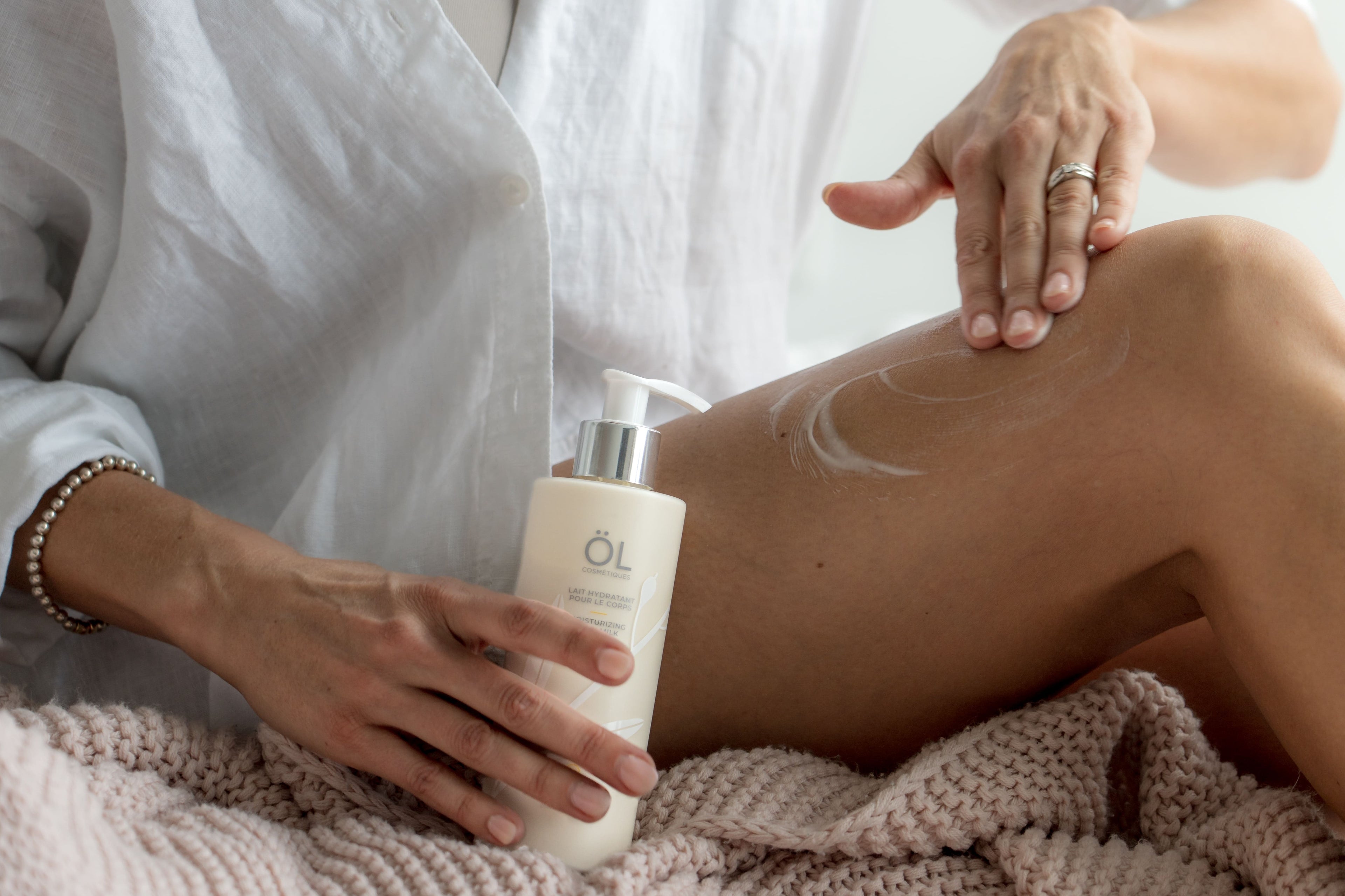 Femme qui applique le lait pour le corps ÖL cosmétiques sur sa peau