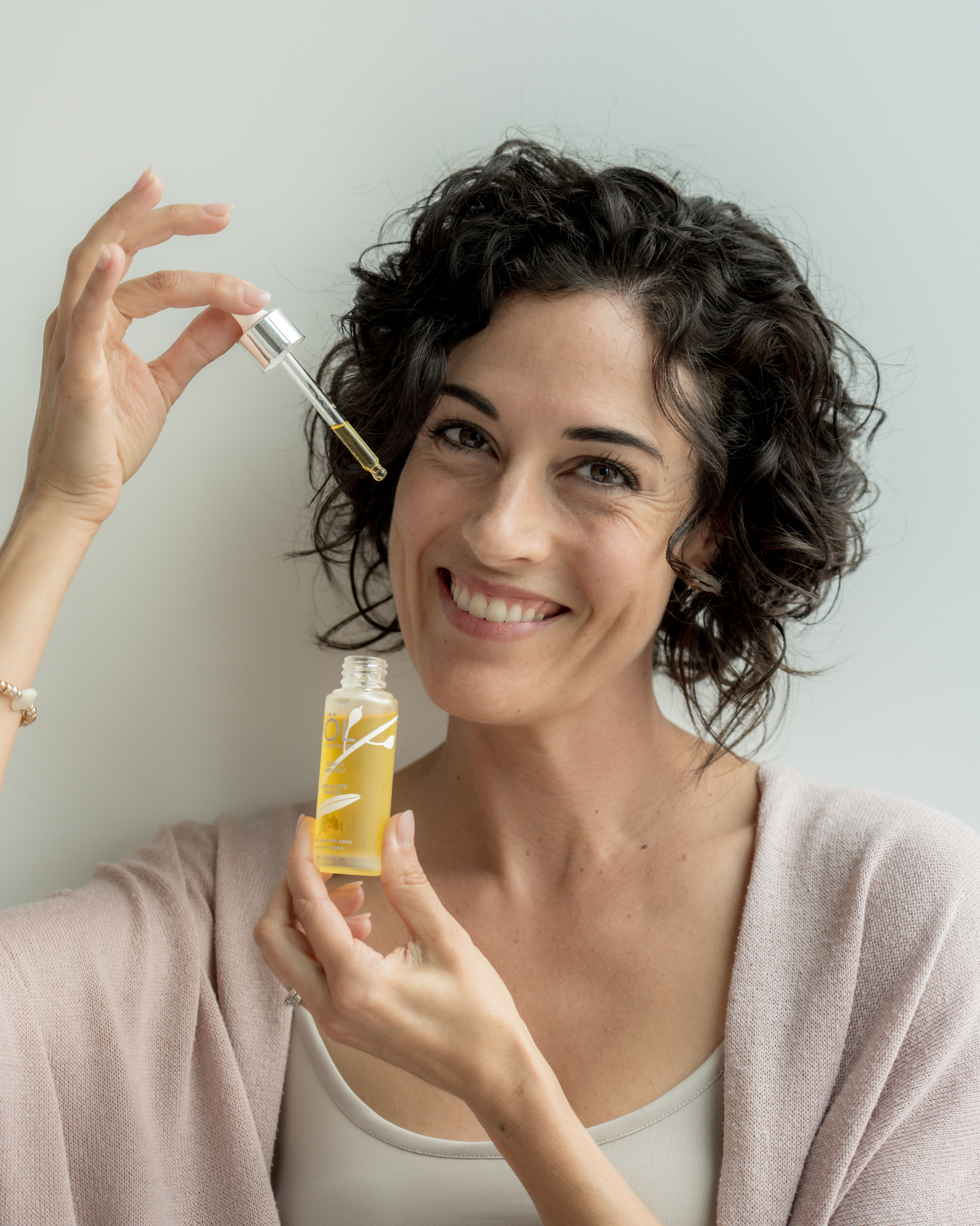 Femme souriante qui applique un sérum sur son visage