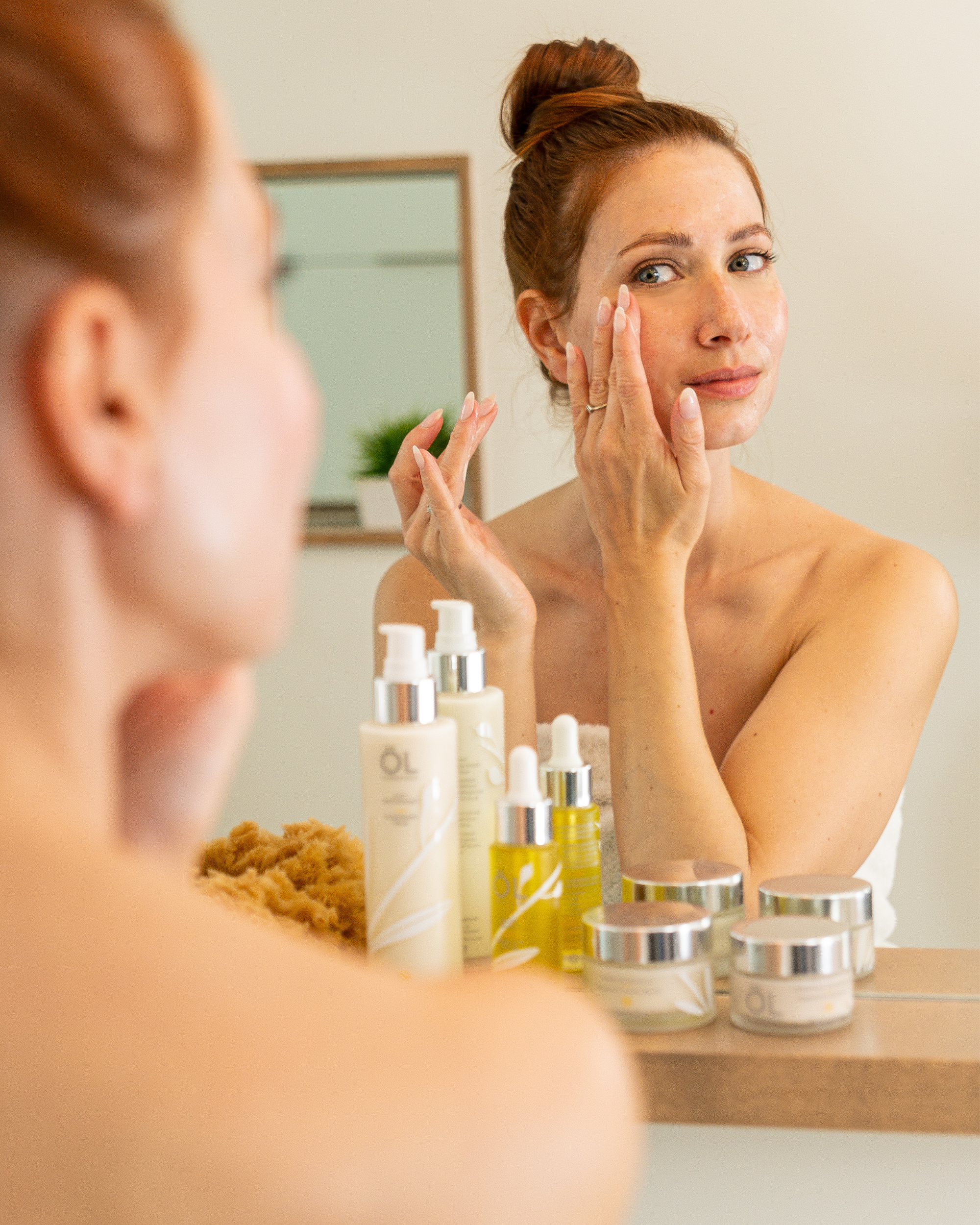 Femme qui utilise les soins de la peau ÖL cosmétiques pour son visage